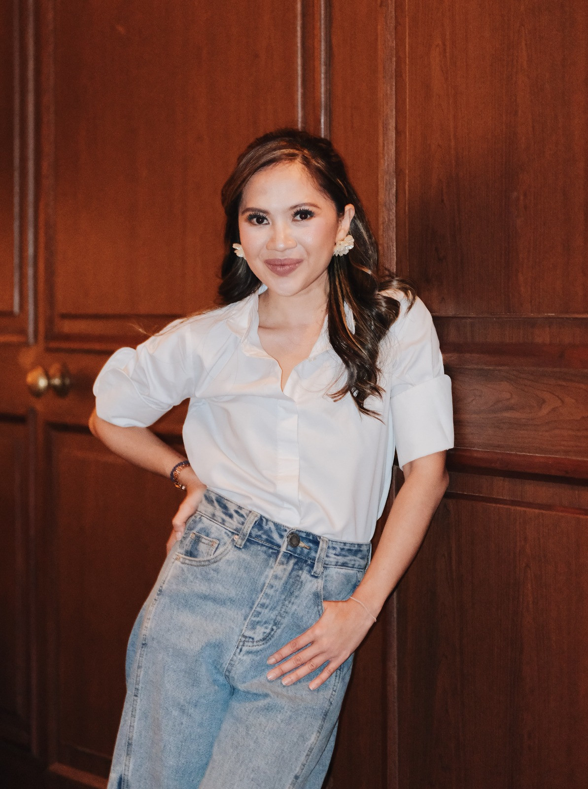 A woman in a white shirt and light-wash jeans embodies modern professionalism.