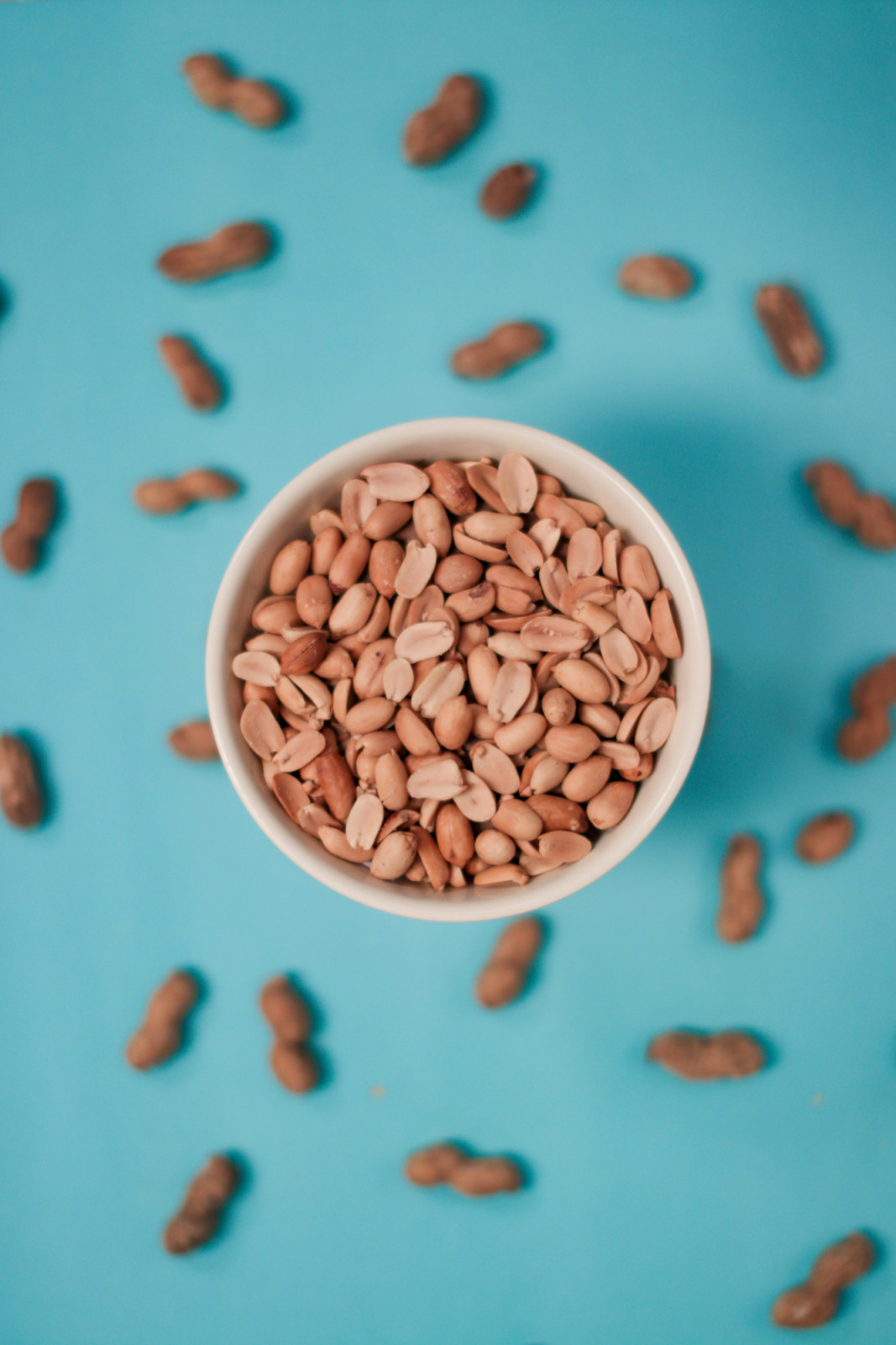 Shelled peanuts in a bowl, accompanied by whole pods, offer a popular snack.