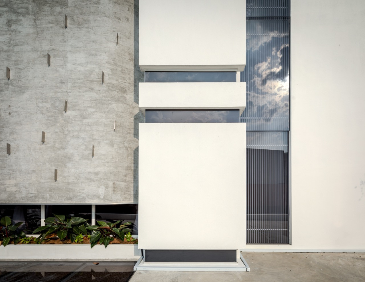 A detail of the front facade, where the bare-board-formed concrete wall meets the smoother white planes elsewhere on the building