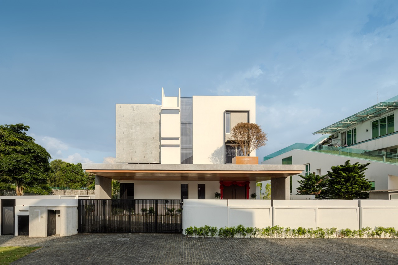 The front of Lotuspure House, with its covered entrance and layered massing of white render and exposed concrete