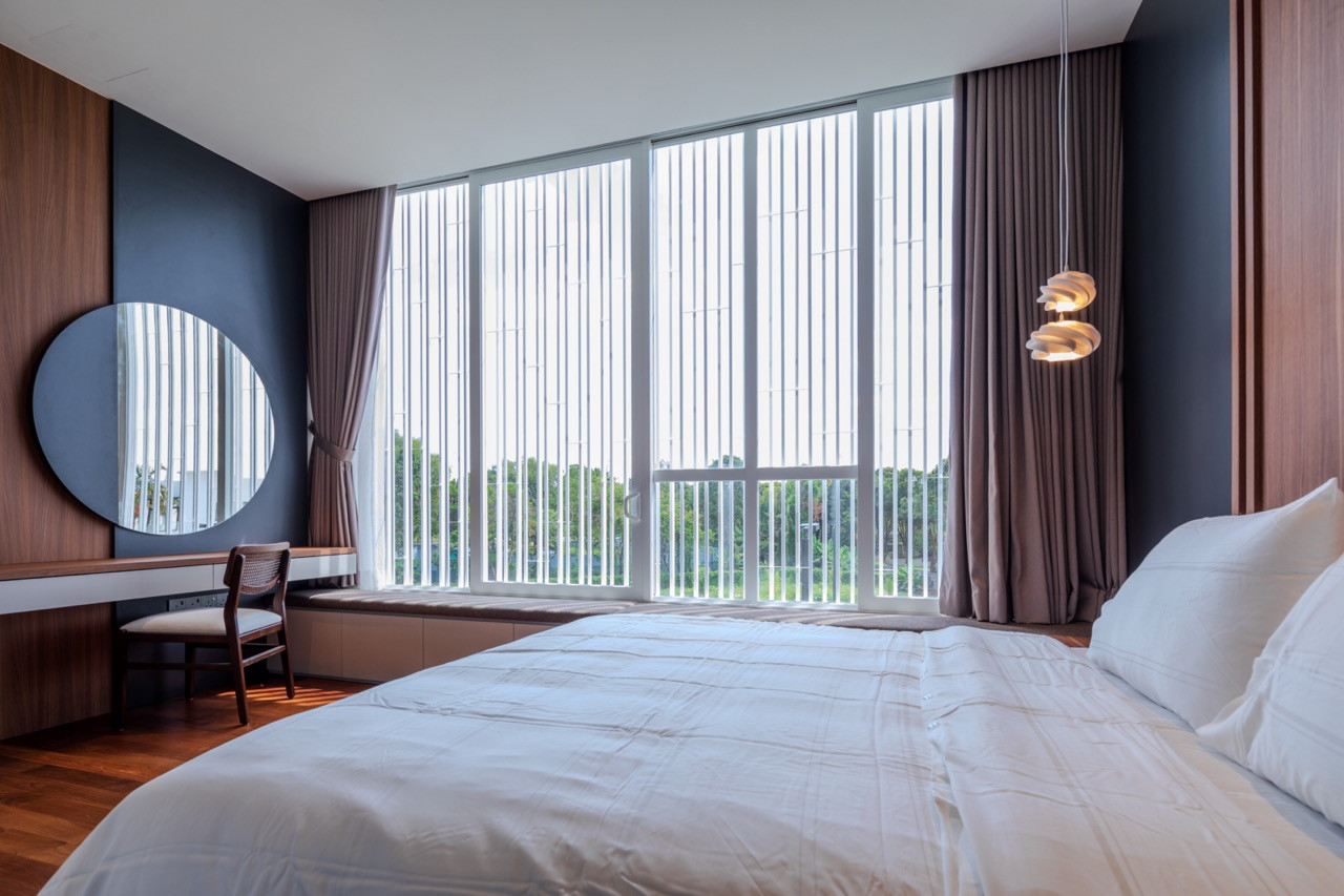 A bedroom fitted with a vertical louvred screen that filters daylight and views toward the garden beyond