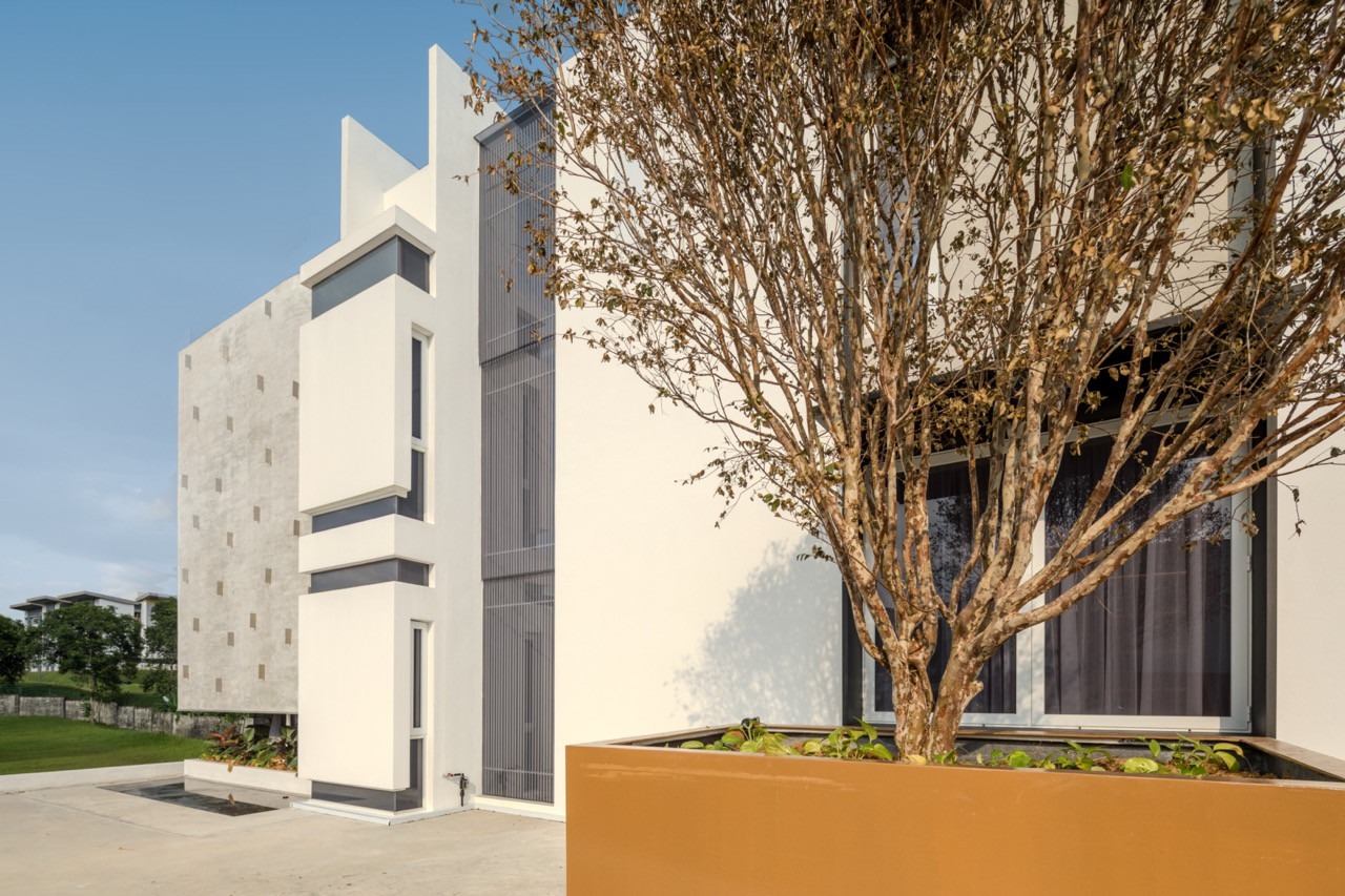 A side view of the house, showing the layering of concrete, white render and louvred screening across its exterior