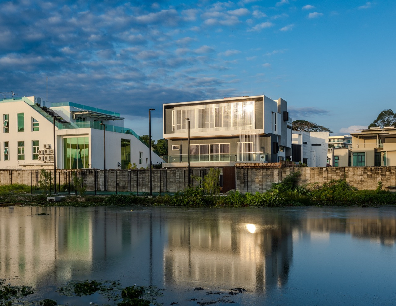 The house reflected in the pond at dusk, its western facade catching the last of the day’s light