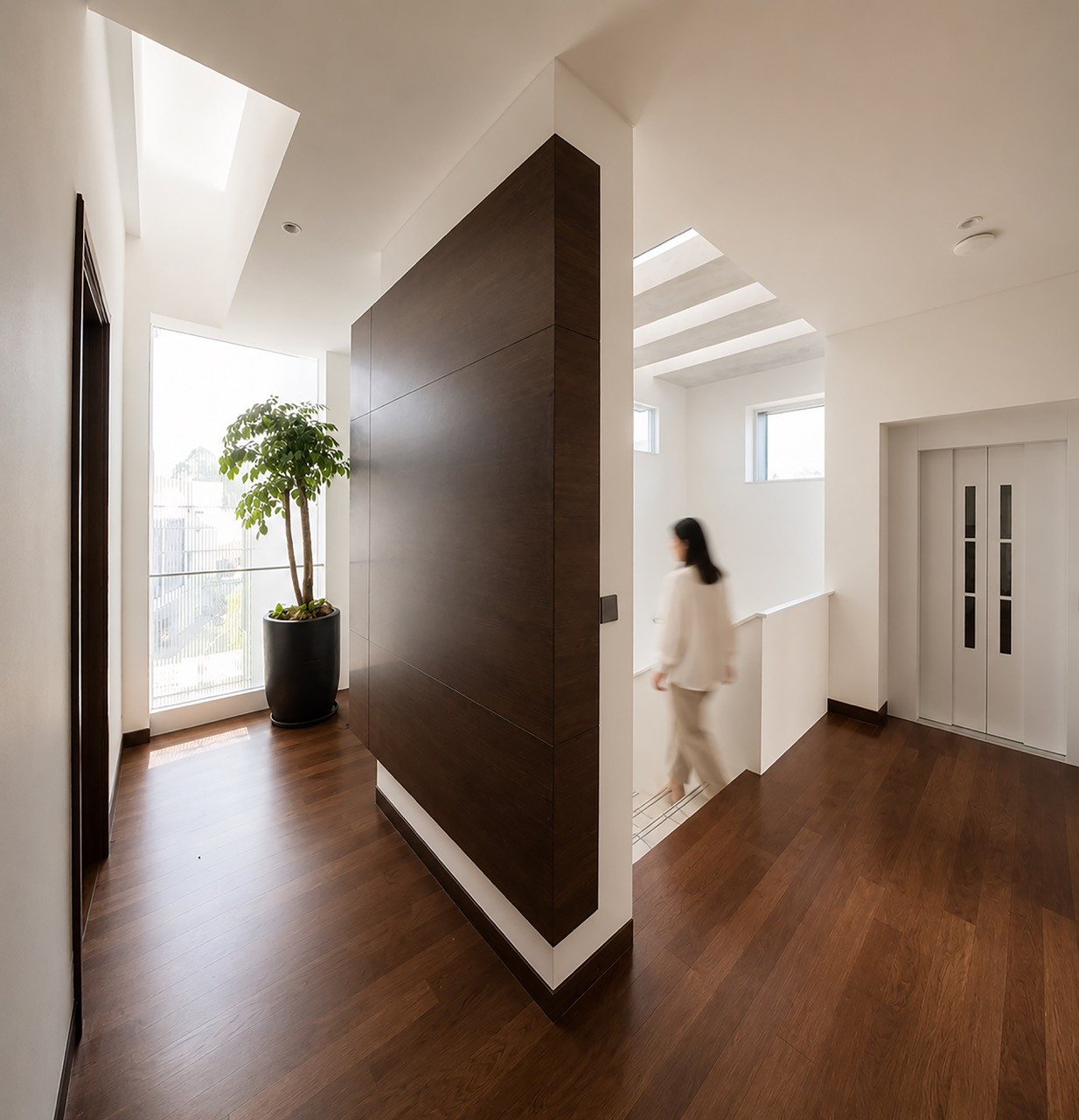 An upper-level hallway, where a freestanding timber panel divides the landing from the stairwell and lift