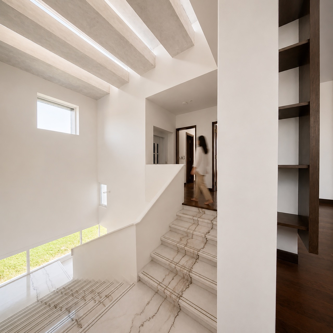 A view down the stairwell toward the marble-clad stairs, with an open bookshelf built into the adjoining