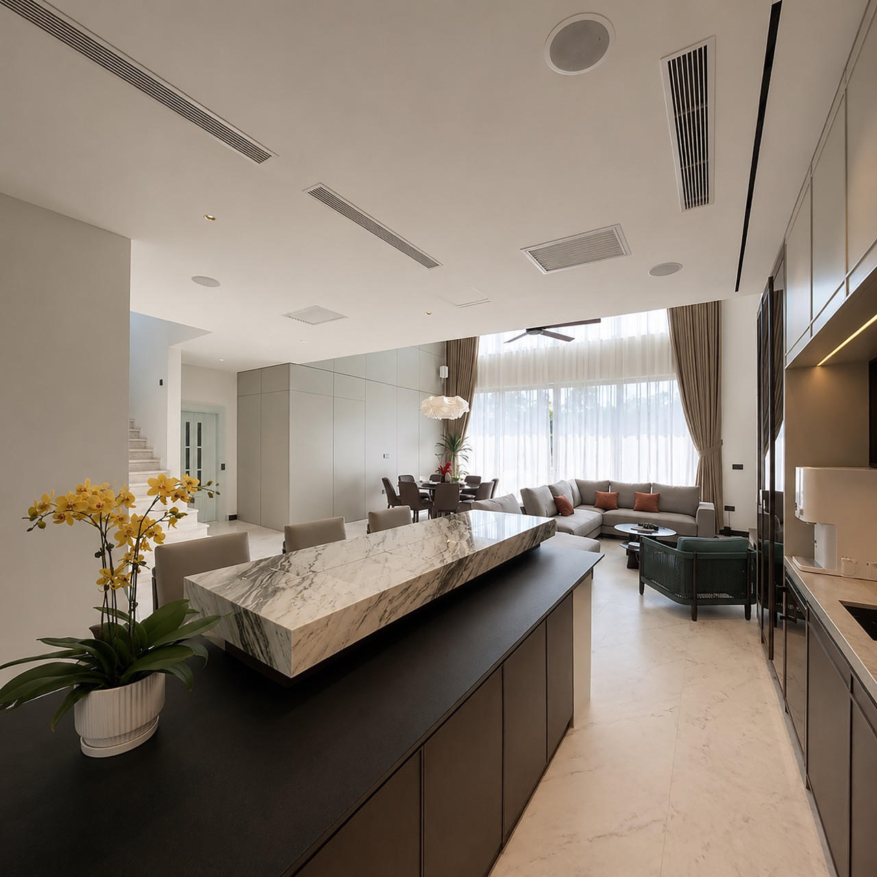 A marble-topped kitchen island in the foreground, with the living and dining area visible beyond
