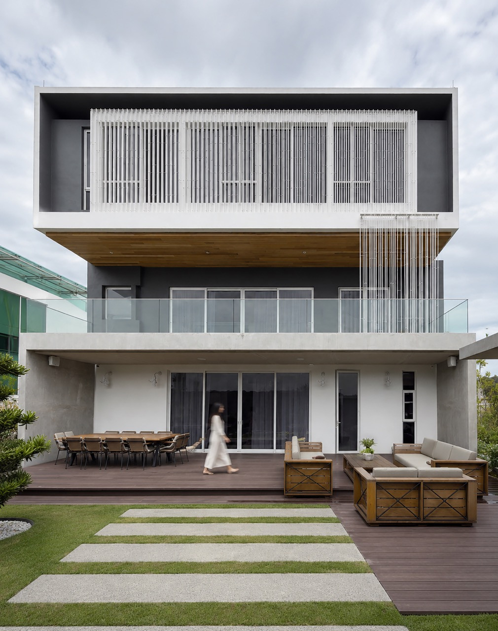 The rear terrace, with an outdoor dining table and lounge seating set beneath the layered upper floors of the house