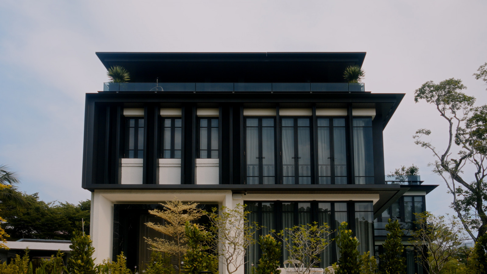 Designed by ACO Architects, the front elevation pairs a monochrome palette with a rooftop terrace and generous windows