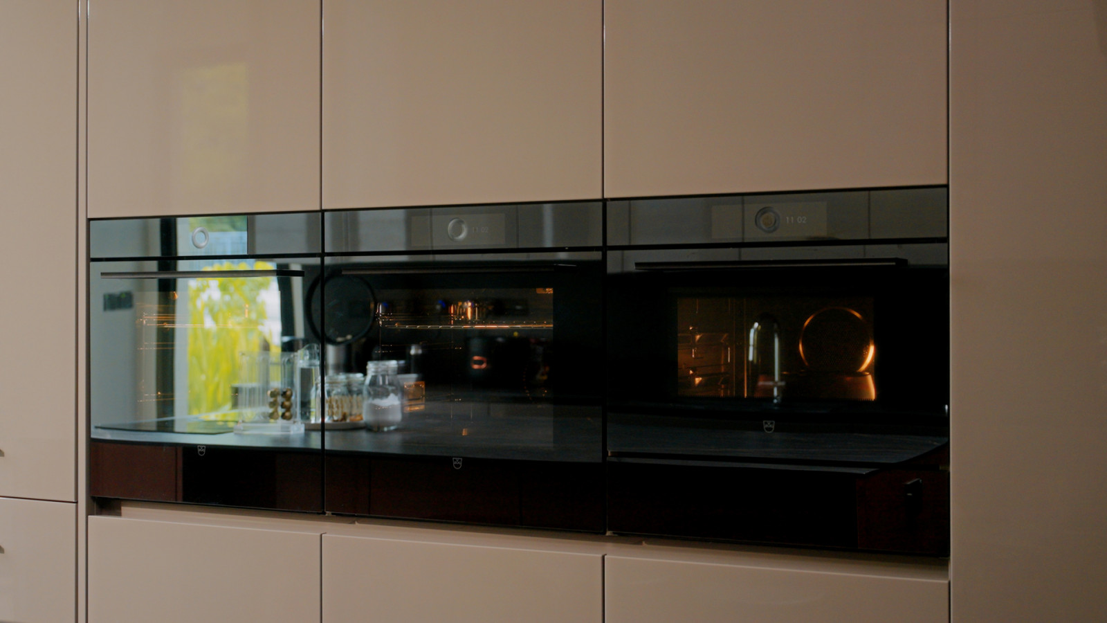 A trio of V-ZUG ovens sits flush within the enclosed kitchen’s glossy cabinetry