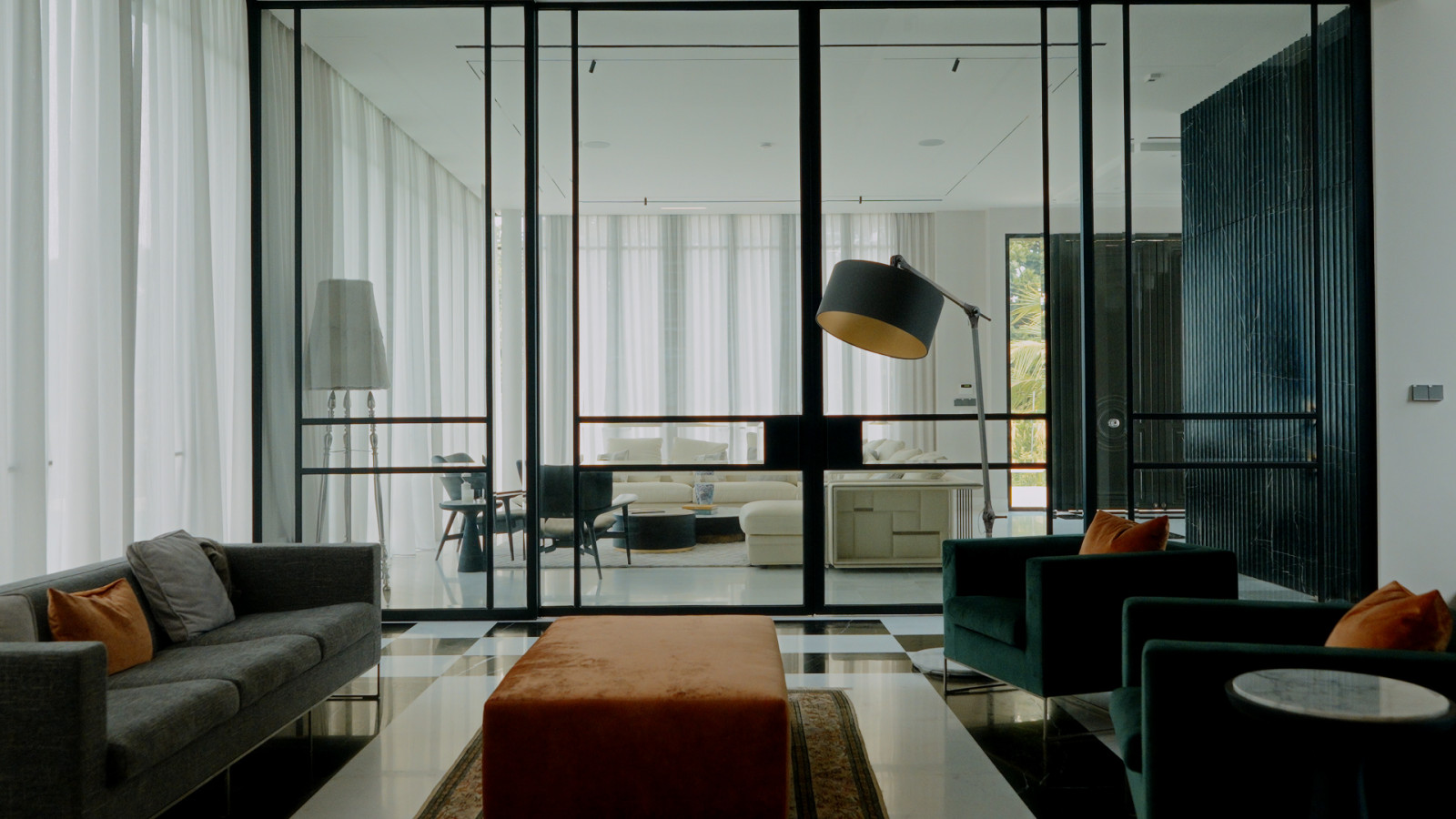 Full-height glass-framed partitions draw the eye from the family room through to the main living area, keeping the household connected across spaces