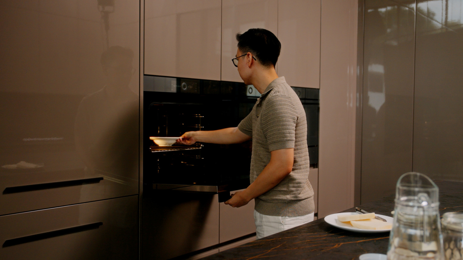 Yuen’s husband slides a dish into the V-ZUG oven in the enclosed kitchen