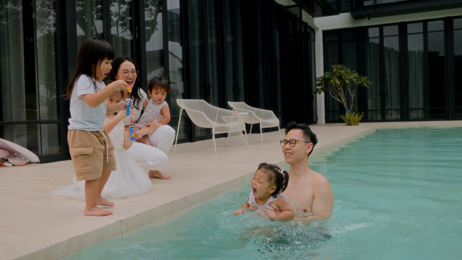 Poolside on a Saturday morning: Yuen’s daughter and two cousins share a splash with her father