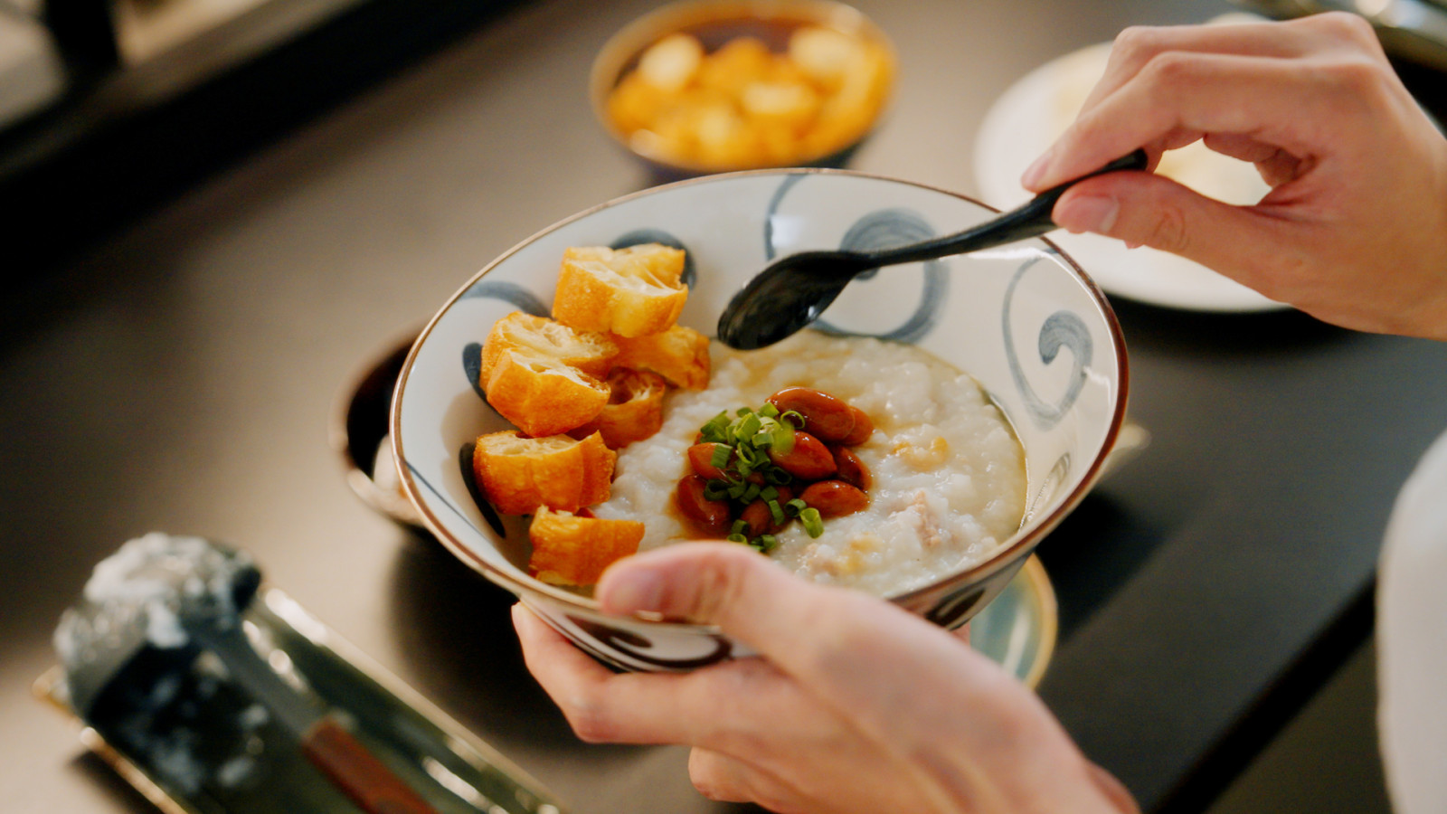A bowl of porridge with you tiao, braised peanuts and spring onions, kept warm on the V-ZUG cooktop until the family is ready