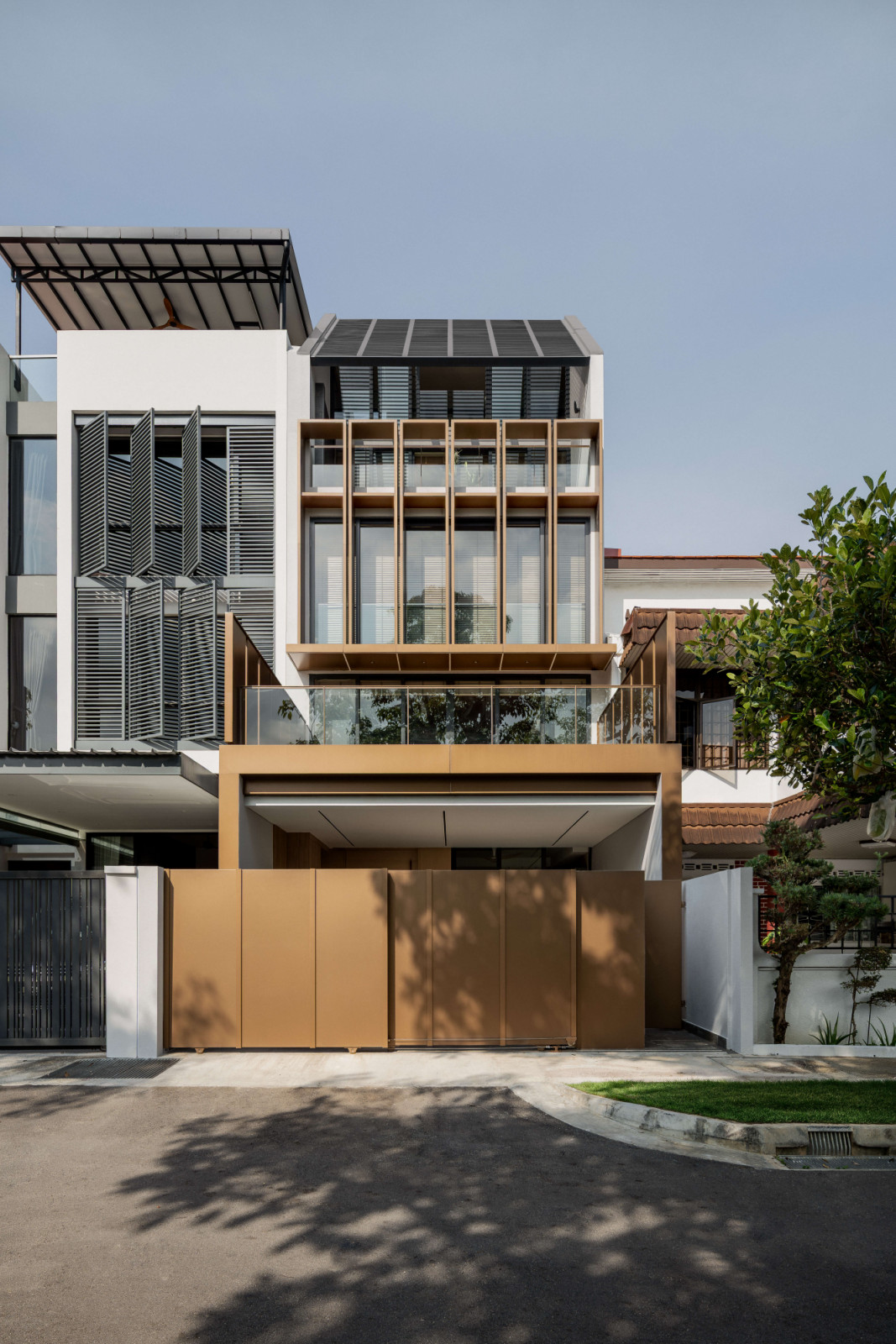 The home's framed façade is defined by layered bronze-toned elements, vertical fins and recessed, deeply framed openings
