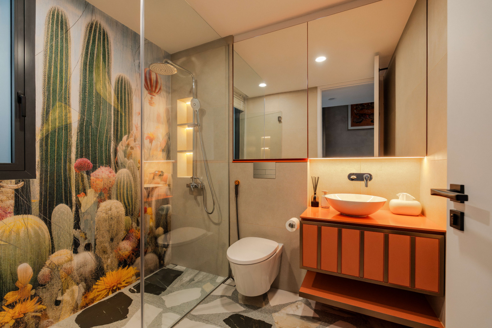 This cactus-inspired bathroom, with its vivid orange vanity and organic black-and-white floor tiles, is an example of playful details incorporated throughout the residence