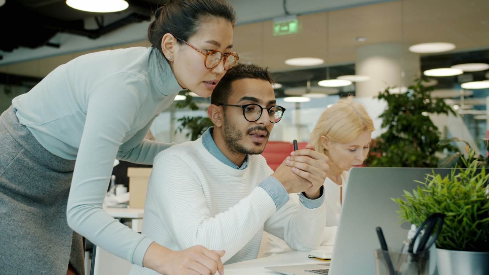Two colleagues collaborate on a project at an office workstation.