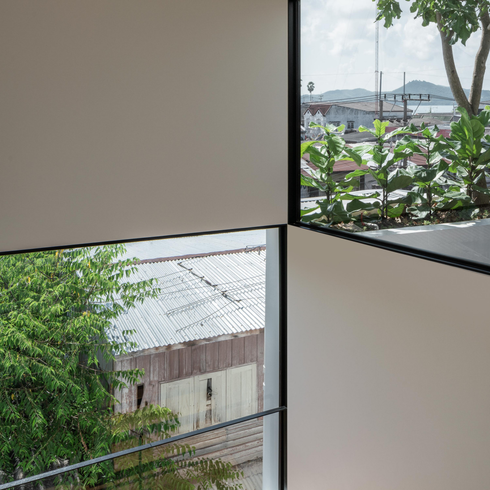 มุมมองจากหน้าต่างที่ถูกตีกรอบ (Framed view) อย่างตั้งใจ ให้เห็นต้นไม้และหลังคาบ้านข้างเคียง เสมือนเป็นงานศิลปะที่เชื่อมโยงกับบริบท (ภาพ: Chalermwat Wongchompoo | Sofography)