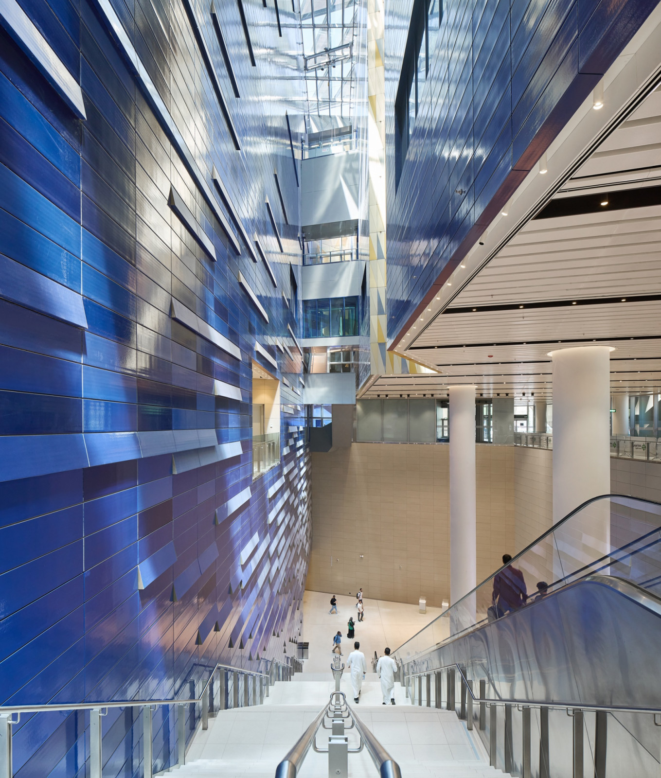 Escalators and stairs run alongside a wall of faceted blue panels inside National Museum Station in Riyadh (Photo: Hufton+Crow)