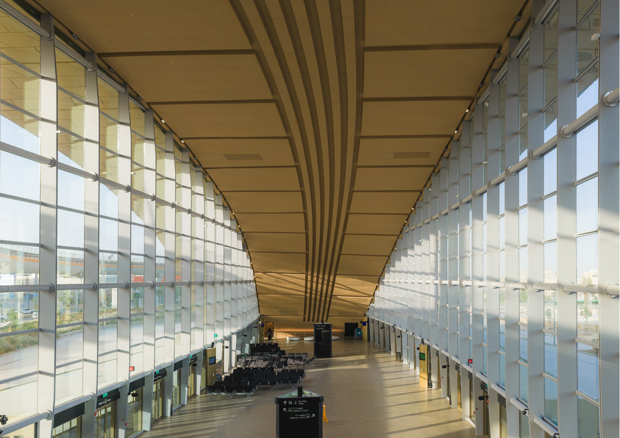 Ribs in the ceiling run the length of a glazed concourse at Western Station in Riyadh, where full-height windows overlook the surrounding site (Photo: Omrania)