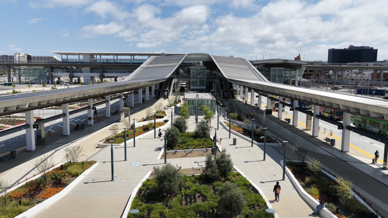 Planted beds and walkways run down the centre of the bus plaza at the LAX/Metro Transit Center in Los Angeles, with bus bays on either side under long canopies (Photo: Jason O’Rear)