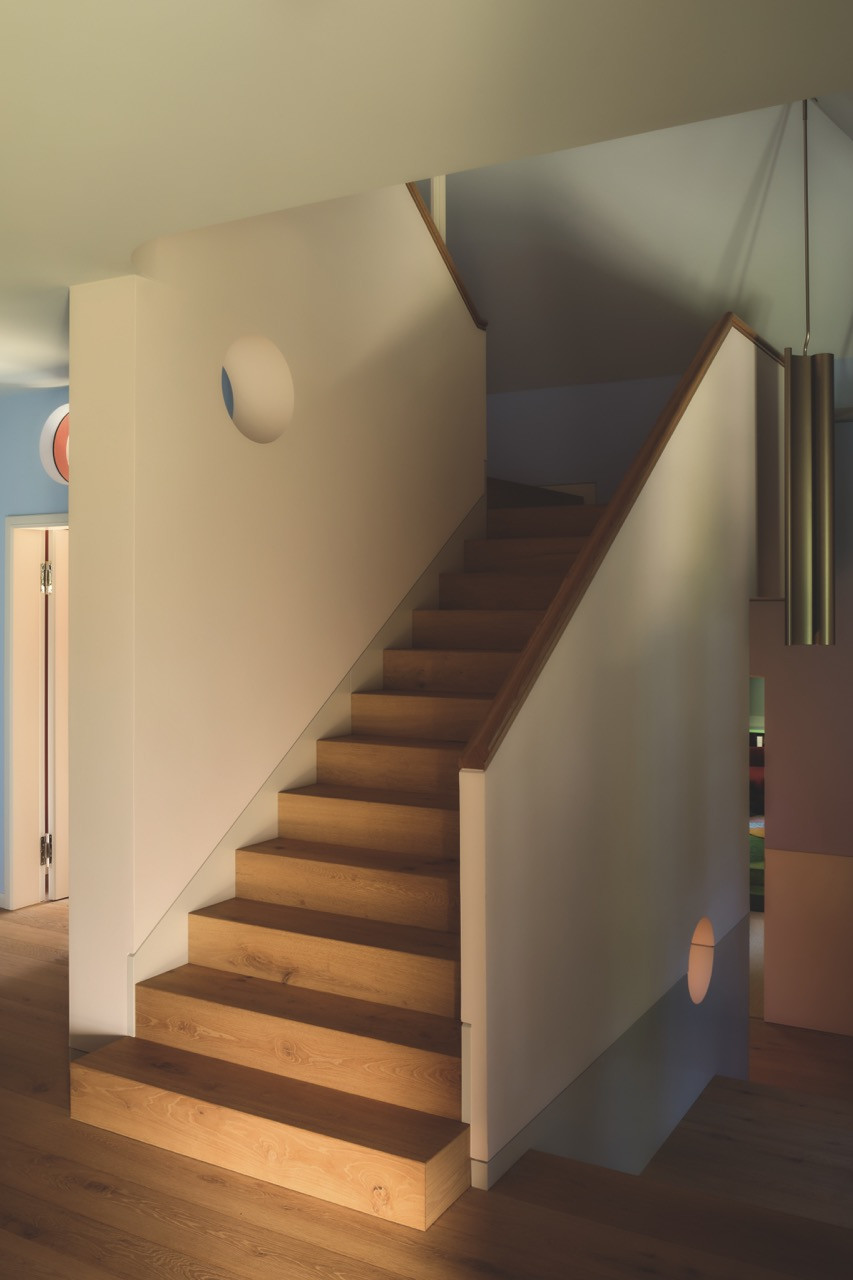 A round window cut into the stairwell wall echoes the villa’s curved detailing
