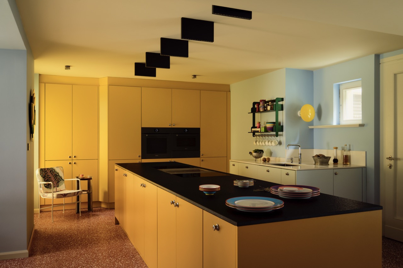 The lemon-yellow kitchen is fitted with a staggered black ceiling detail above the island