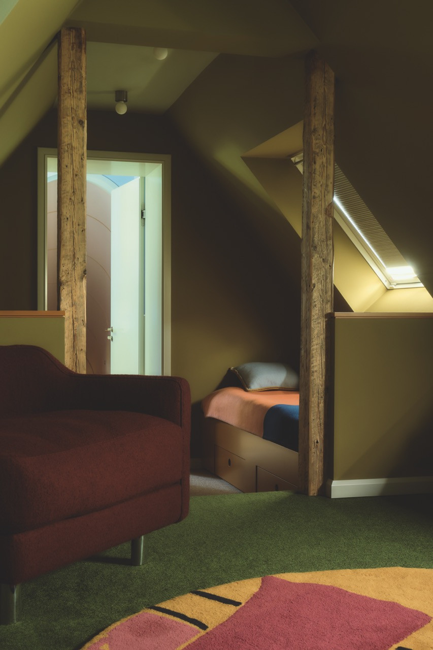Reclaimed wood beams frame a built-in bed in one of the upper floor's private rooms