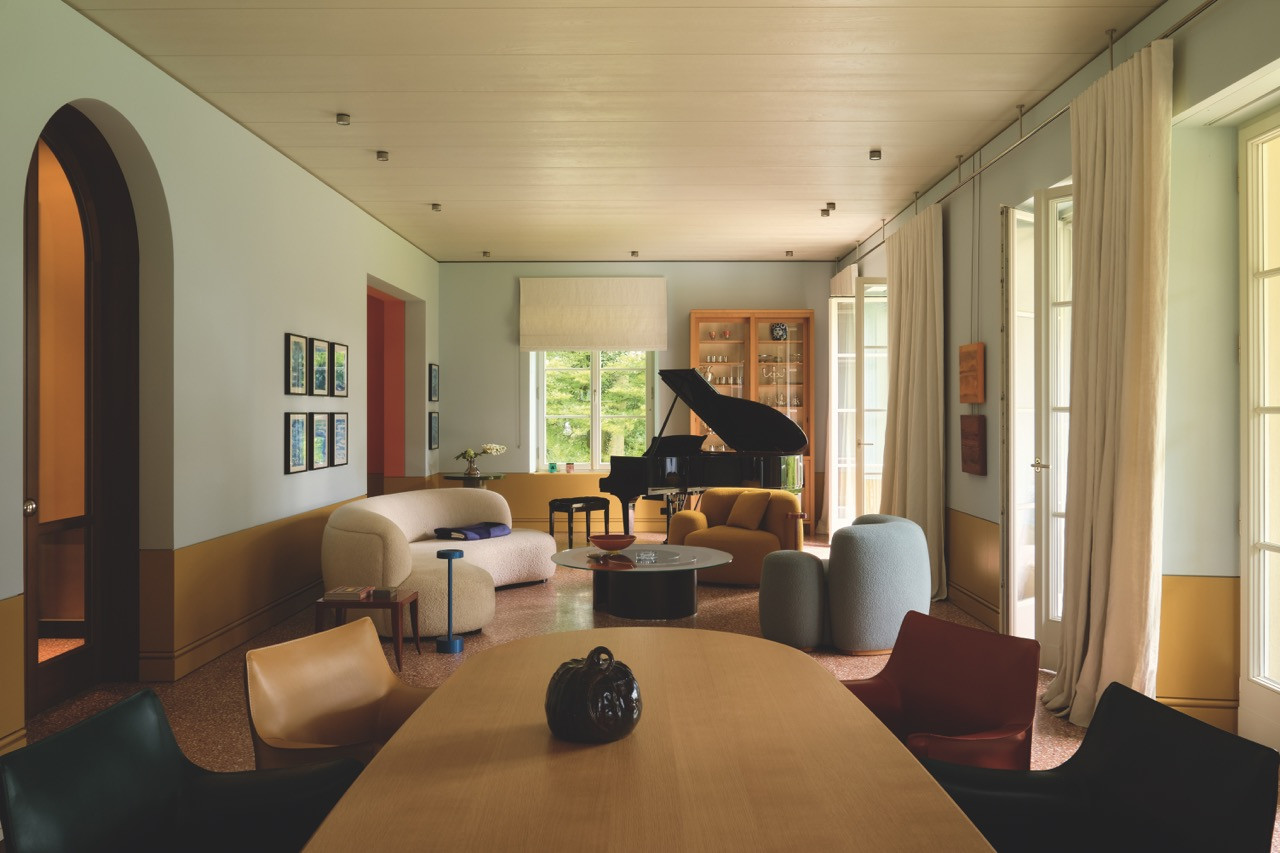 A curved sofa and grand piano share the living hall, its floor finished in terrazzo with purple accents