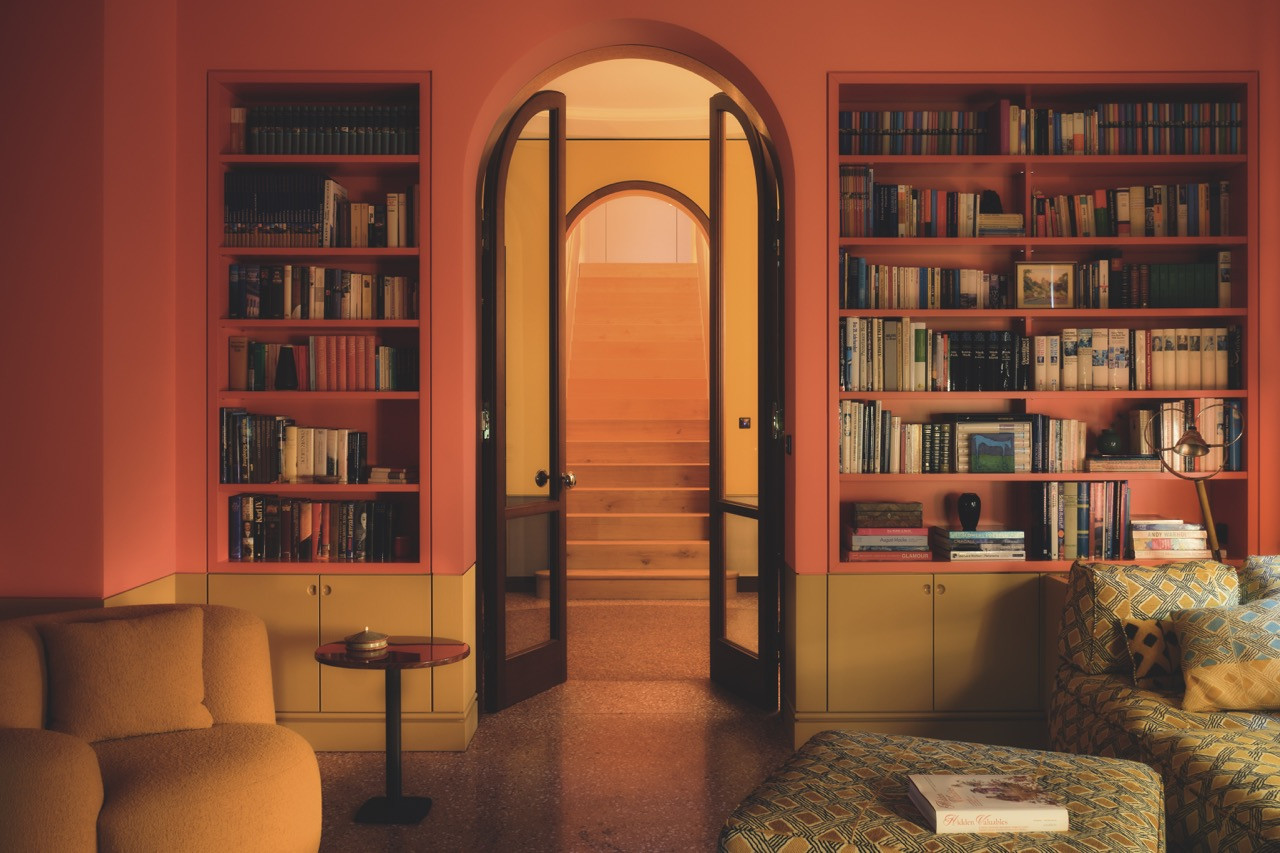 Orange bookshelves flank an arched doorway leading to the staircase