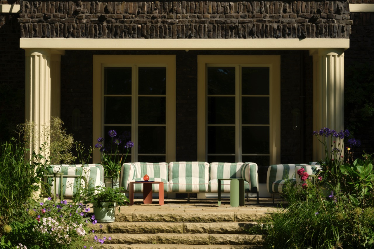 Striped outdoor seating is arranged beneath umbrellas on the columned terrace