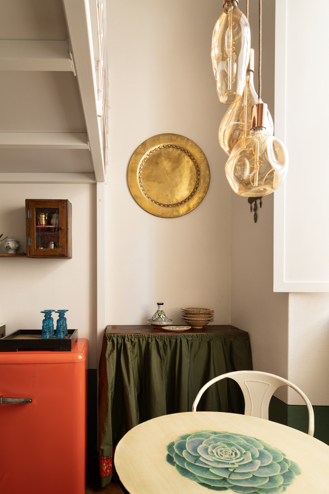 A compact flame-red refrigerator and a salvaged cabinet enhanced with Moroccan fabric