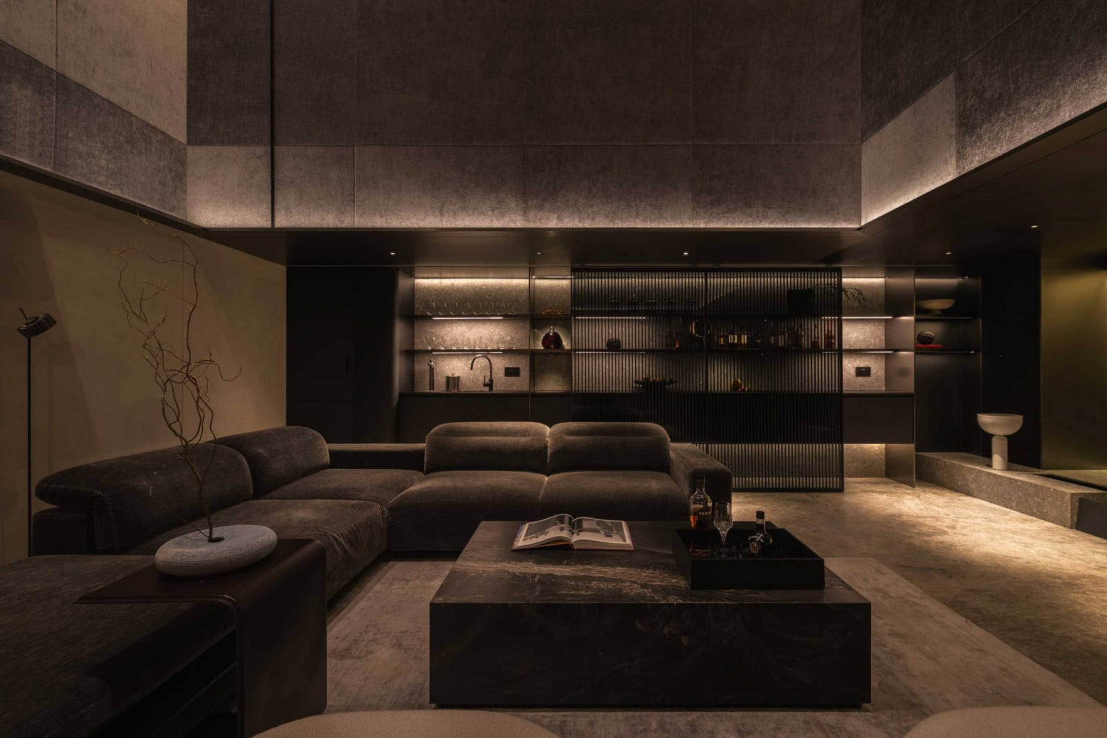 The entertainment room’s concealed speakers and built-in bar sit within a moody, textured backdrop