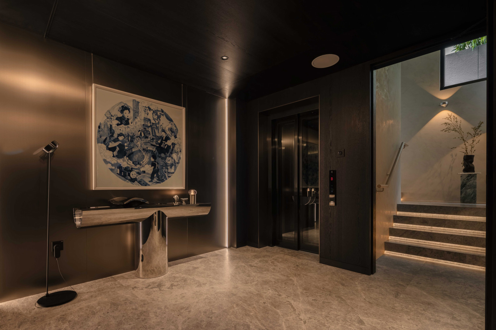 The basement lift lobby pairs a sleek, polished console with a framed abstract artwork
