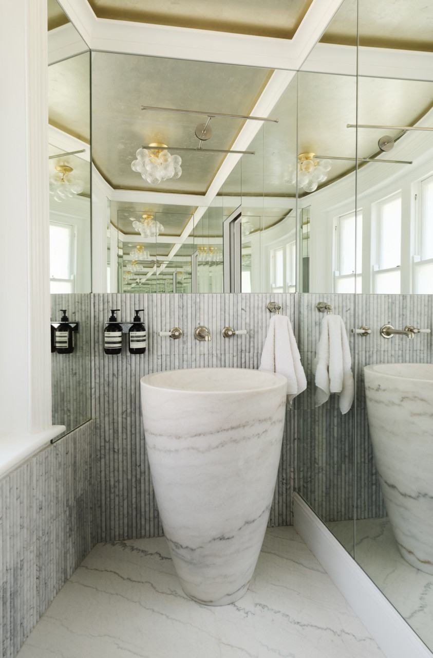 A freestanding marble basin, fluted marble tiles and a metallic leaf ceiling in one of the bathrooms, where the dining-room paper reads silver