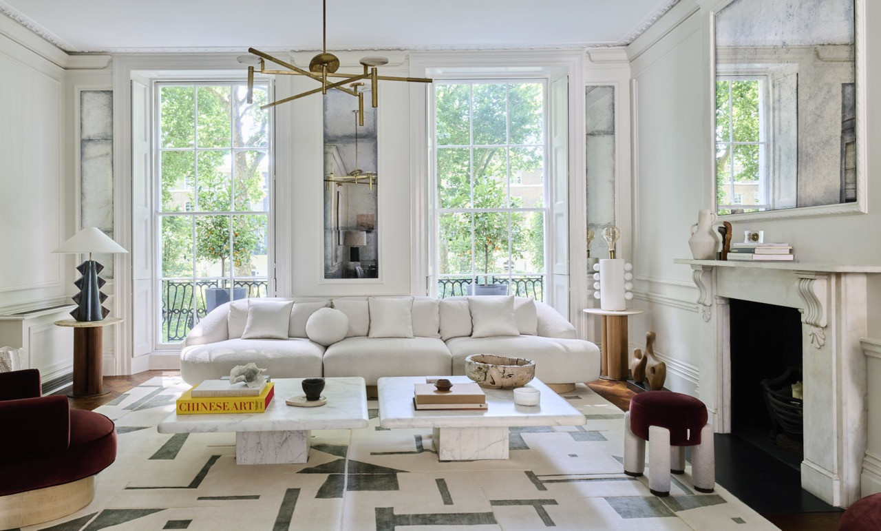 Thick-edged marble coffee tables from Dara Maison sit at the centre of the living room, flanked by the original fireplace and windows onto the square