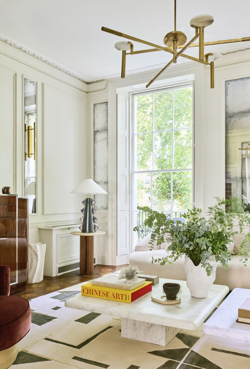 Tall sash windows look onto the square’s garden, with a brass chandelier above twin marble coffee tables