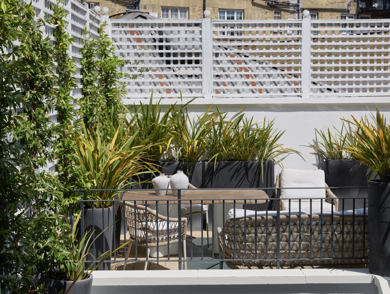 The rear terrace, rebuilt after its rotten boards gave way, is screened with trellis and planted with grasses