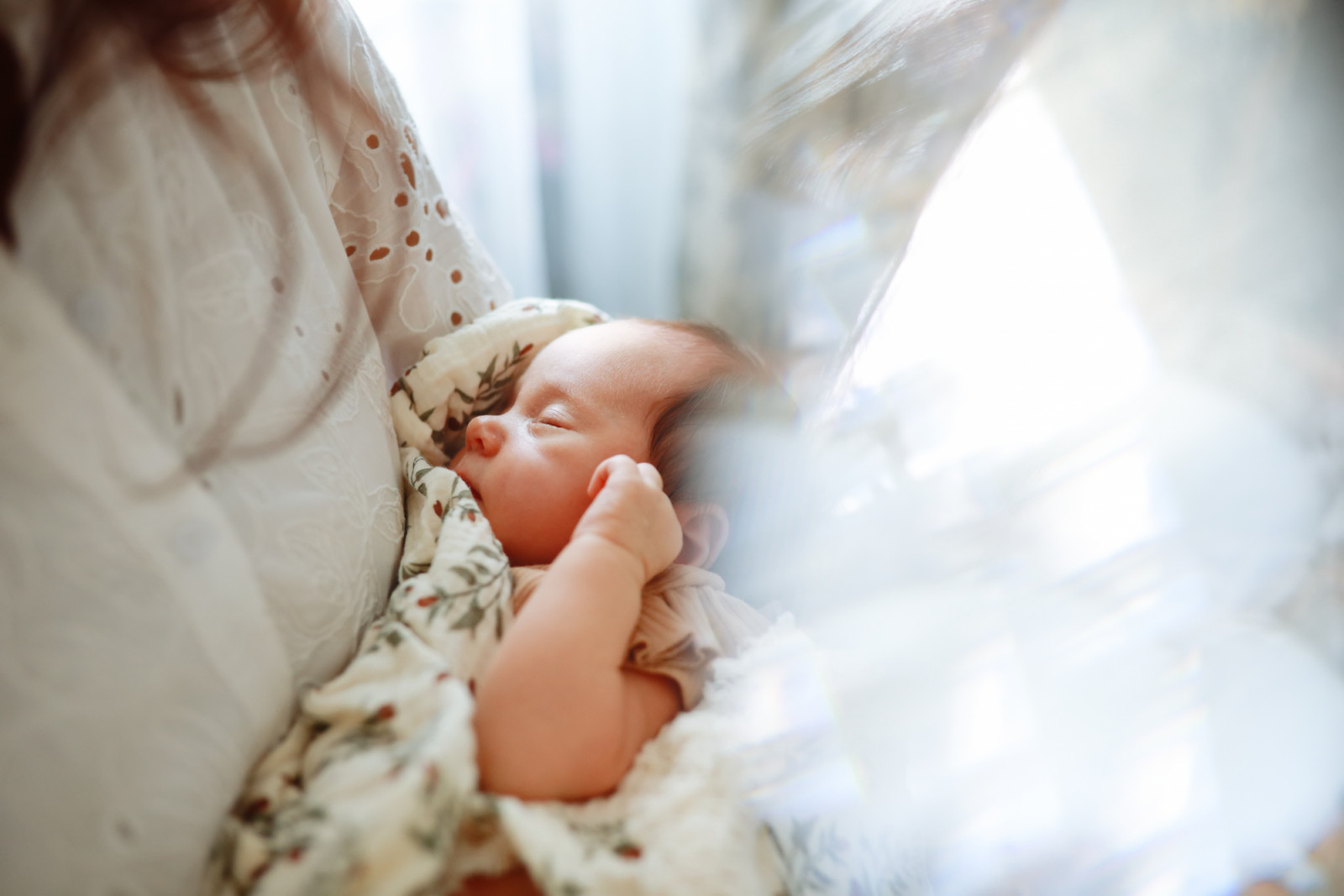 sleeping newborn girl in mother's arms, close-up shot