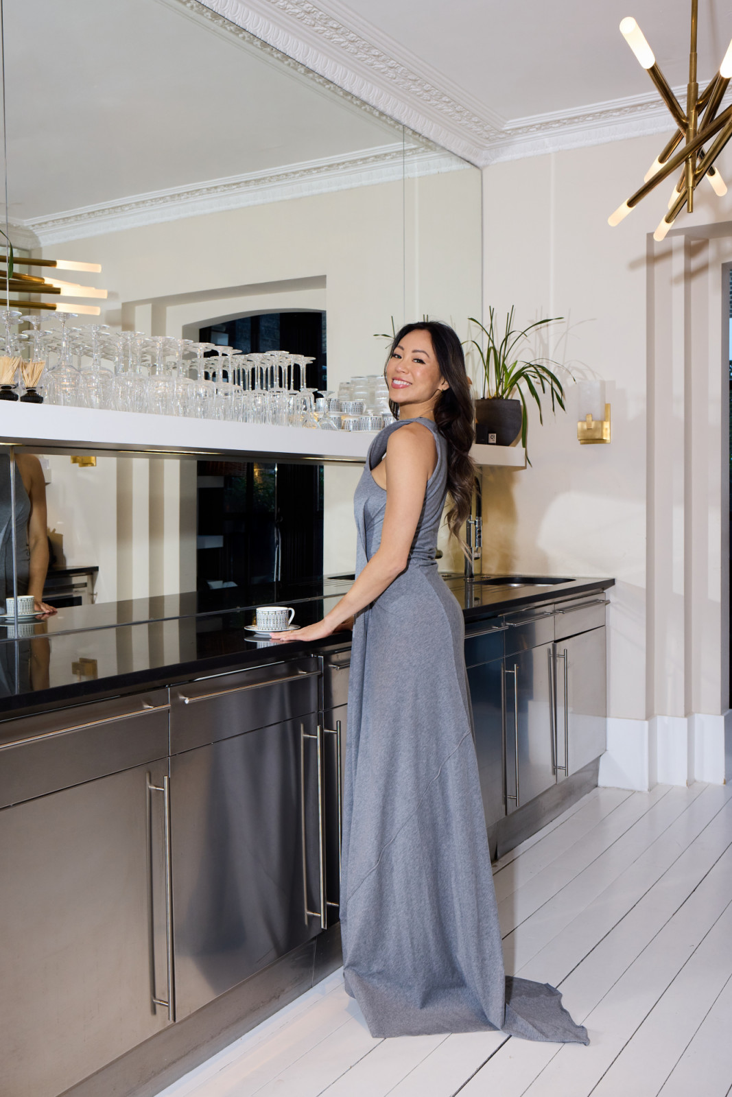 Huang in the kitchen, where stainless-steel cabinetry and a mirrored splashback sit beneath the original plaster cornicing