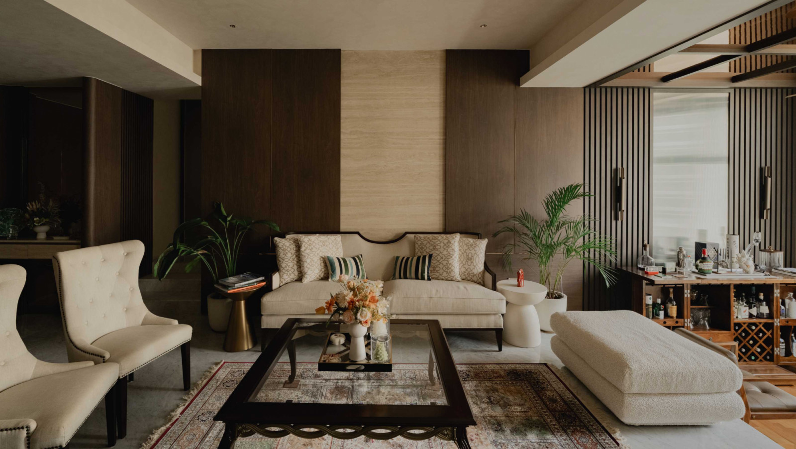 Dark-stained wood, overstuffed cushions and indoor palms imbue the living room of this apartment by Urban Delineation with a soothing, tropical feel