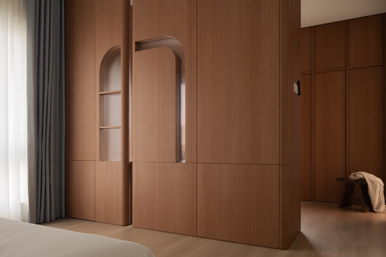 A freestanding wardrobe divides the bedroom; its arched niches are backed with reeded glass