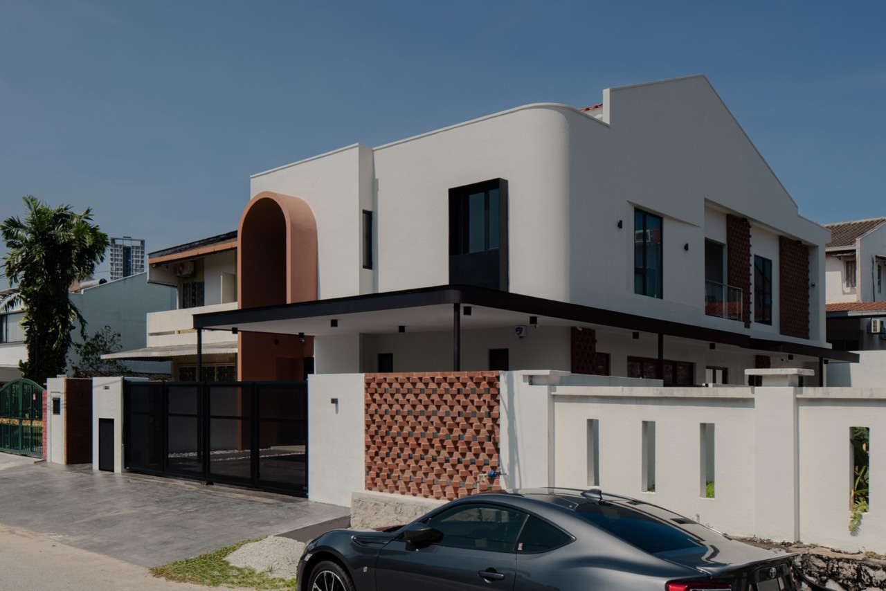 The renovated house, seen from the corner, with red brick screens set into the boundary wall and upper façade