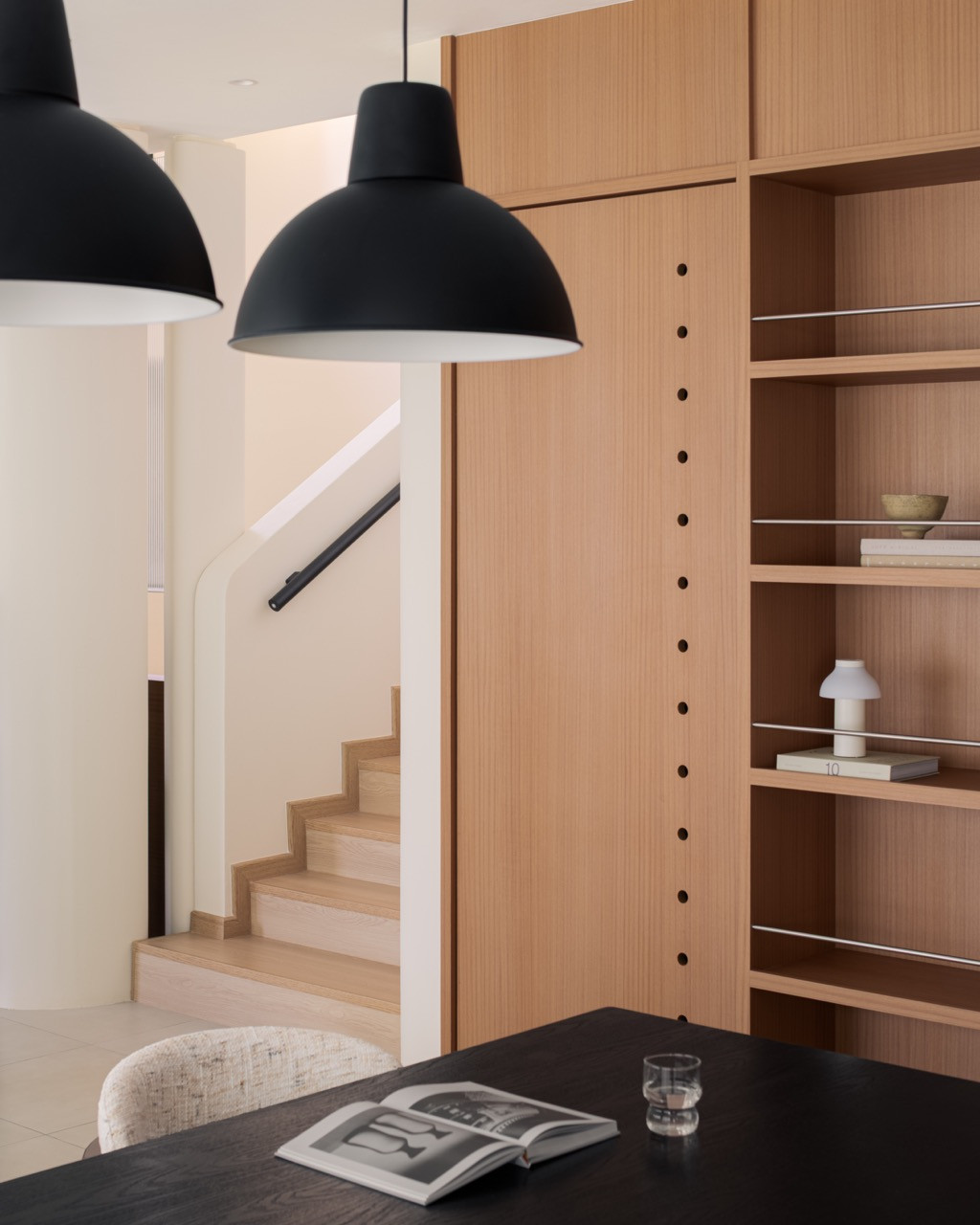 From the dining table, the staircase is visible beyond a wall of built-in shelving