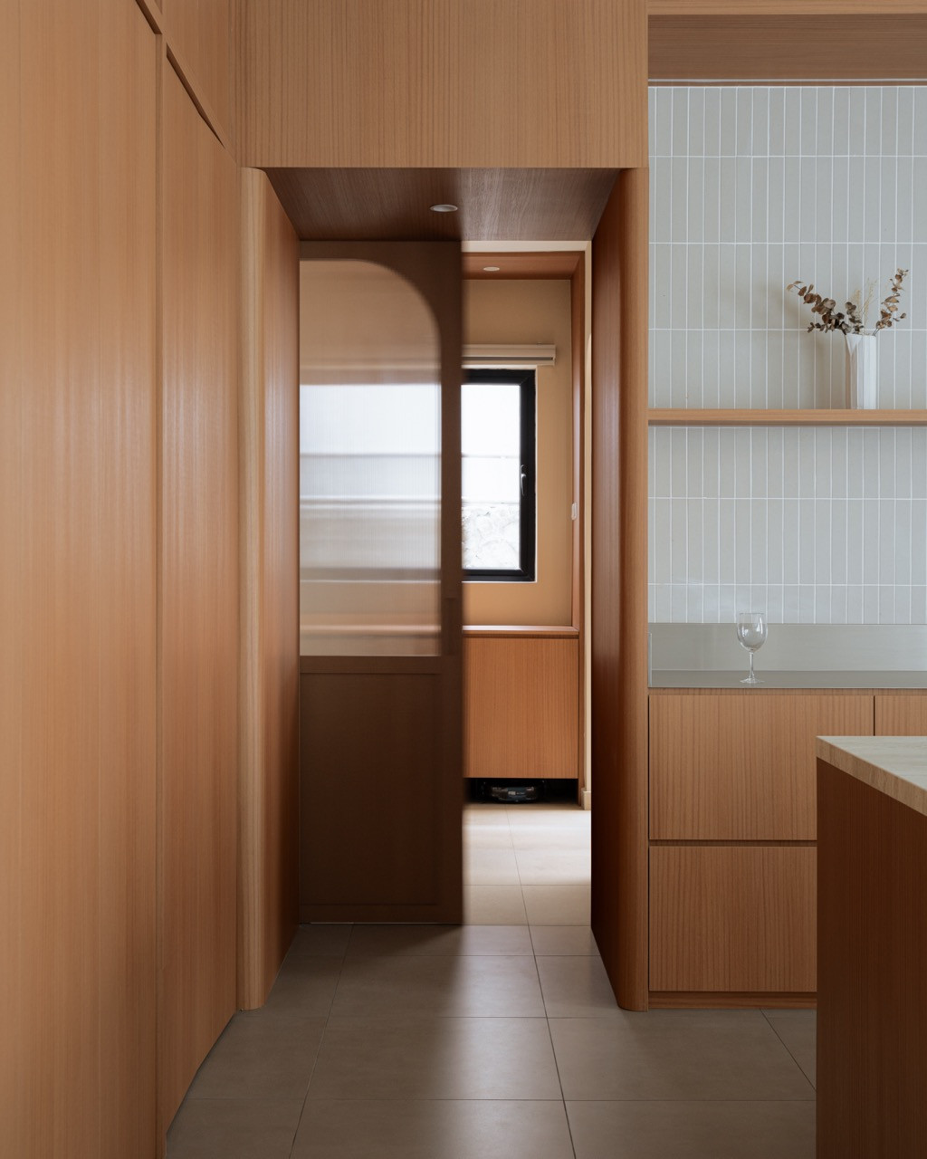 A door with an arched reeded-glass panel slides open between the dry and wet kitchens