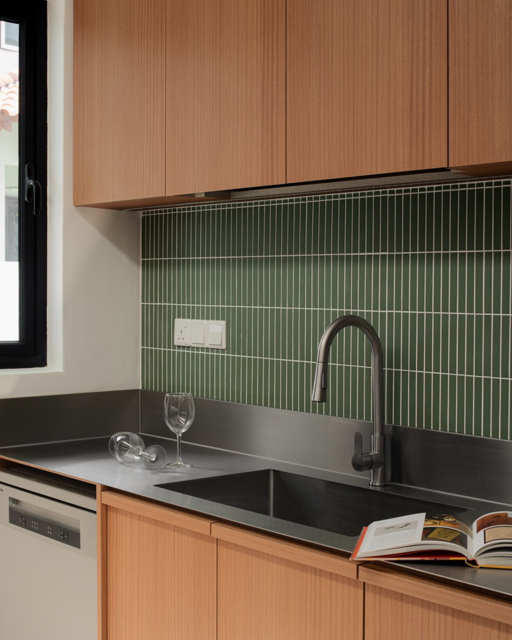 The wet kitchen pairs a stainless steel countertop with green ceramic tiles laid vertically