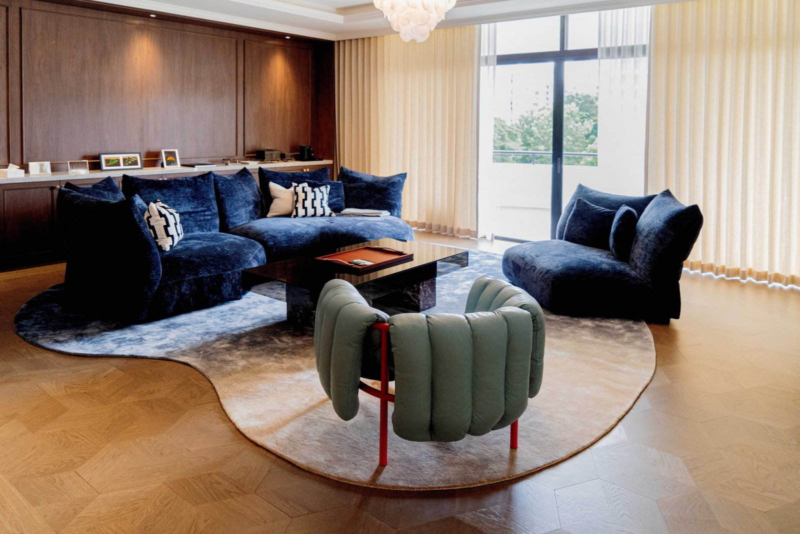 A custom bean-shaped gradient rug in blue and taupe demarcates the living room’s seating area