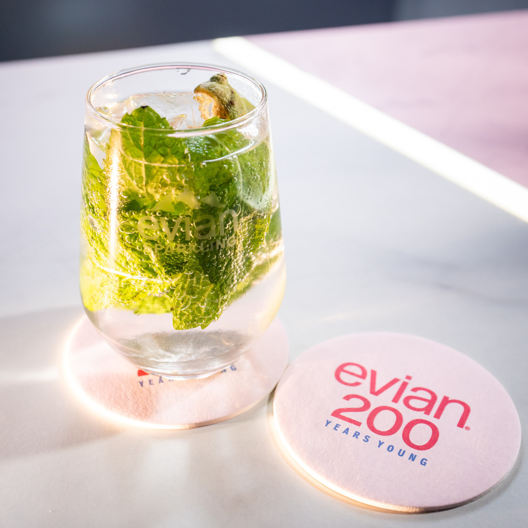 Evian Sparkling water infused with mint and lime, resting on a coaster celebrating Evian's 200th anniversary.