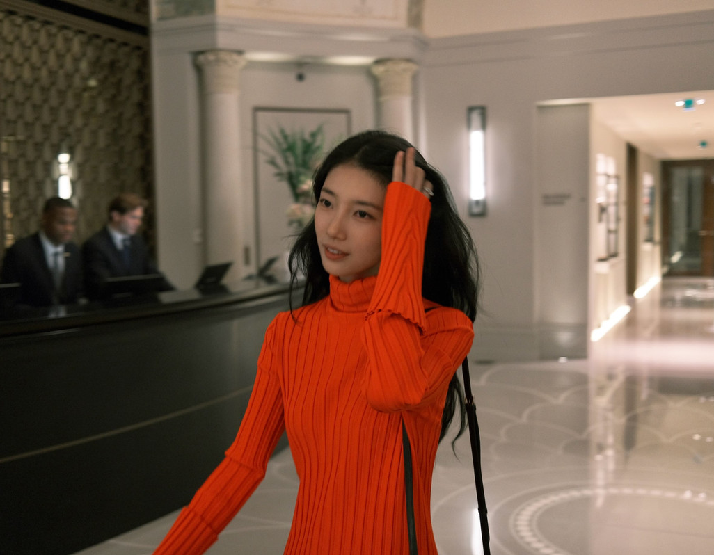 South Korean star Bae Suzy navigates a sophisticated hotel lobby.