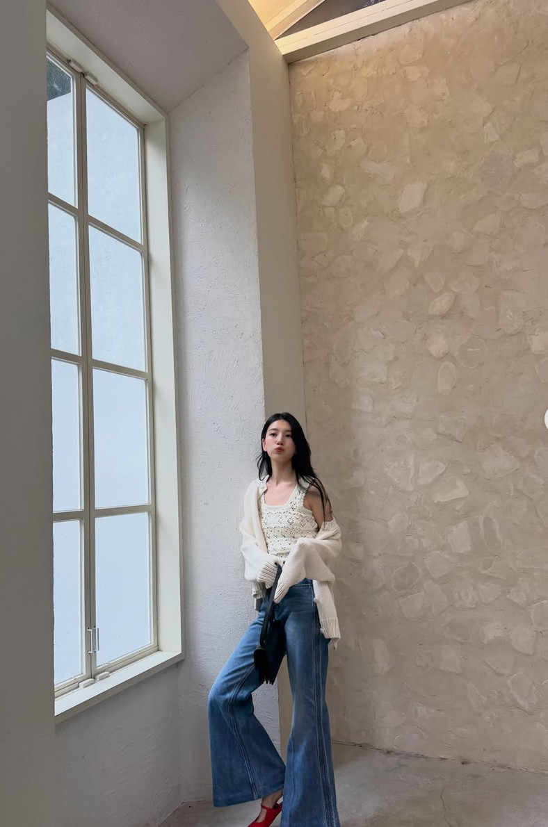 Bae Suzy, actress and singer, wears a cream crochet top, blue wide-leg jeans, and red heels.