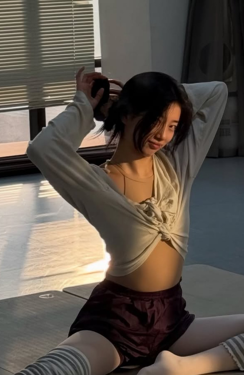 Bae Suzy, the South Korean star, tying her hair in a sunlit room.